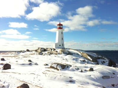Ein beliebtes Ausflugsziel: Der Leuchtturm in Peggy's Cove Weißer Leuchtturm im Schnee an den Klippen zum Atlantik