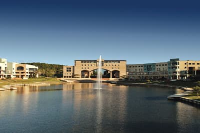 Der Campus der Bond University bietet den Studierenden malerische Momentaufnahmen. Ein Gebäude der Bond University hinter einem Teich mit einer großen Fontäne