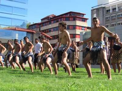 Verschiedene Kulturen an der Uni in Auckland Studierende in traditioneller Maori-Kleidung vor modernen Gebäuden