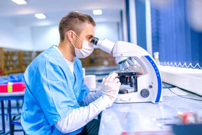 Die Arbeit mit Laborgeräten wie Mikroskopen ist in vielen naturwissenschaftlichen Fächern ein fester Bestandteil des Studiums. Chemiker bei der Arbeit mit einem Mikroskop in einem chemisch-pharmazeutischen Labor