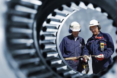 Eintauchen in die Welt der Technik: Ein ingenieurwissenschaftliches Studium macht es möglich. Mechaniker vor einer großen Zahnradmaschinerie