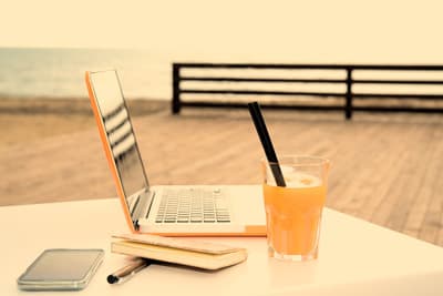 So kann ein Auslandsstudium in der Sonne aussehen Ein Tisch auf einer Terrasse mit Laptop und sommerlichem Getränk