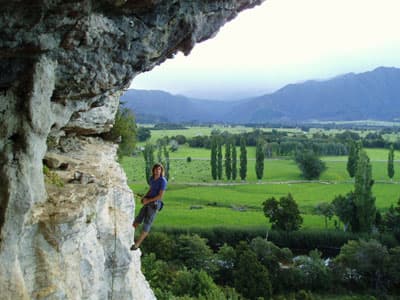 Für alle die hoch hinaus wollen Student klettert weit oben auf einem Felsen vor sehr grüner Landschaft