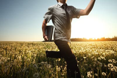 Ein Auslandsstudium vermittelt wertvolle Soft Skills, die auch Datenwissenschaftler brauchen Student läuft mit Laptop über Blumenwiese