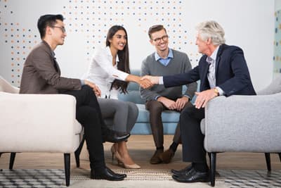 Studenten sitzen mit einem Mann in einer modernen Sitzgruppe