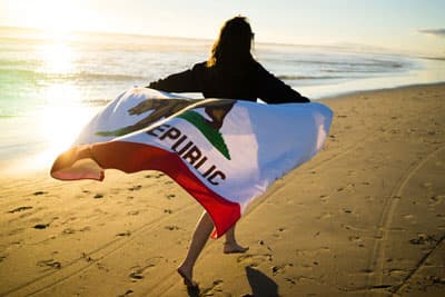 Meer, Sonne, Strand - das verspricht ein Auslandssemester an der University of California Irvine Studentin am Strand mit California Flagge