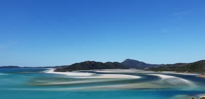Der Whitehaven Beach Ein weißer Strand am türkisen Meer mit Bergen im Hintergrund