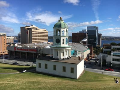 The old town clock am Citadel Hill Ein alter Uhrturm vor einer modernen Downtown.