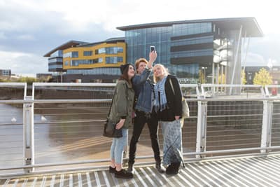 Stolz auf ihren Campus: Studenten der USW in Newport Studenten machen ein Selfie vor ihrem Unigebäude am Newport City Campus
