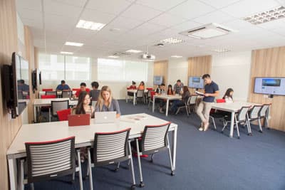 Eine Studyarea der JCUS Ein Raum mit Tischen, Stühlen und mehreren Fernsehern