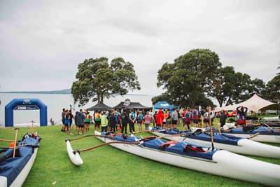 Mit dem Waka raus aufs Meer! Traditionelle neuseeländische Kanus auf einer Wiese bei der Waka Ama Competition der University of Auckland