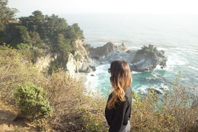 So Cal - so much to do! Studentin vor einer felsigen und grün bewachsenen Küstenlandschaft in Kalifornien