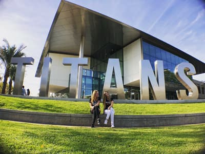 Werdet Mitglied der Titans-Family! Studentinnen vor "Titans"-Skulptur auf dem Campus der CSUF