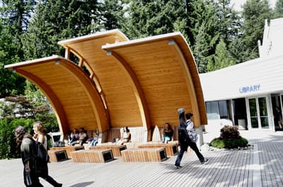 Passt sich an seine natürliche Umgebung an: der Campus der CapU Wellenförmige Holzkonstruktion vor der Bibliothek der CapU. Hinter dem Gebäude beginnt der Wald.