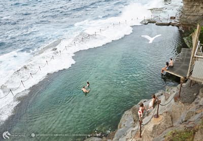 Plantschen im Meerwasser-Pool Das Bogie Hole ist ein in den Fels geschlagener Badepool, der vom Meer durch einen Zaun abgetrennt ist. Die Wellen schwappen in das Becken, in dem Badegäste plantschen.