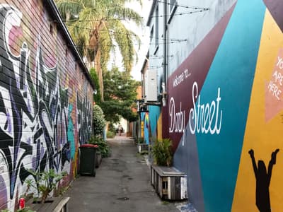 Newcastle kreativ Graffiti-bemalte Wände mit Palmenpanorama, Sitzgelegenheiten und Lichterkette in einer kleinen Seitenstraße der hippen Darby Street