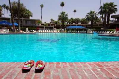 Badespaß in Palm Springs Ein Pool in einer Freizeitanlage mit Flipflops am Beckenrand