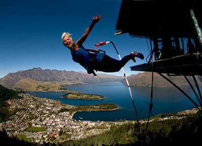 Abenteuerliche Südinsel! Junge Frau macht Bungee-Jumping vor wunderschönem Berg- und Seenpanorama