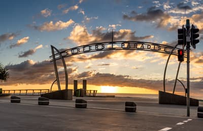 Die paradisische Gold Coast Portal mit der Aufschrift "Surfer's Paradise" bei Sonnenuntergang.