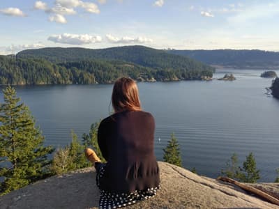 Kanadas unberührte Natur Eine Studentin sitzt auf einem Felsen und genießt den Ausblick über den Ozean und zahlreiche kleine bewaldete Inseln