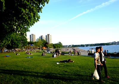 Grüne Großstadt Gut besuchte Wiese und Strand im Stanley Park mit Skyline im Hintergrund