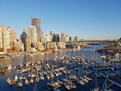 Zahlreiche kleine Boote und eine große stählerne Brücke vor der Skyline Vancouvers.