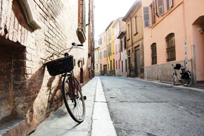 Ganz einfach das Leben genießen! Ein Fahrrad lehnt an einer Hauswand in einem schmalen Gässchen im italienischen Ort Piacenza.