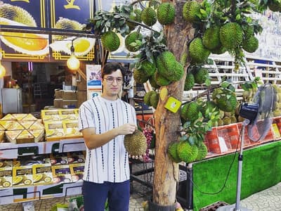 Früchte sind in Singapur sehr beliebt Ibrahim in einem Obstgeschäft, wo die charakteristische Durianfrucht verkauft wird. Sie ist groß, grün und stachelig.