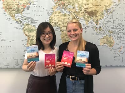 Einfach "better together" Shelley von der JCU Singapore und Stephanie von College Contact zeigen die Flyer der Better Together Kampagne