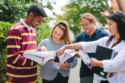 Starke Lerngemeinschaft Internationale Studenten mit Büchern und Mappen bei der Besprechung eines Themas.