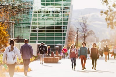 PPE-lern stehen alle Türen offen Studenten laufen über den Campus der University of Otago, vorbei an einem modernen Gebäude mit Glasfassade.