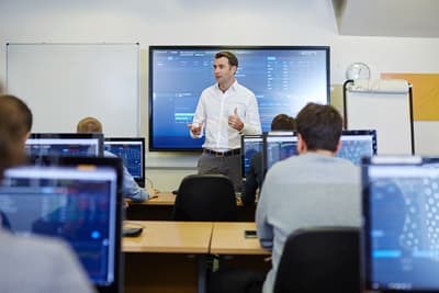 Außerordentliche Möglichkeiten Kurs im Thomson Reuters room der Universität. Die Studierenden arbeiten an jeweils eigenen PCs, während vorne an einem großen Bildschirm erklärt wird.