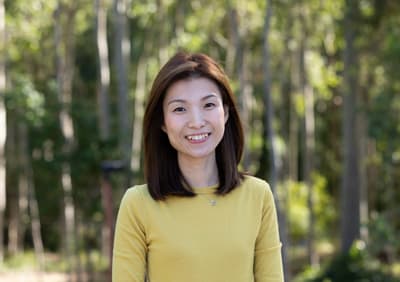 Debbie Choi Porträt von Debbie vor dem grünen Hintergrund des "Bushland Campus" der University of Newcastle.