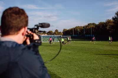 Bereit für das internationale Sportbusiness? Ein Student filmt ein Fußballteam auf dem Feld.
