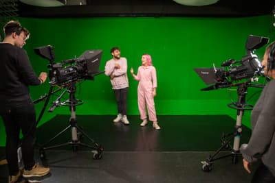 Die Regent's University London vermittelt dir die nötigen Fähigkeiten, um in der Medienbranche durchzustarten. Studierende der Regent's University London vor einem Greenscreen