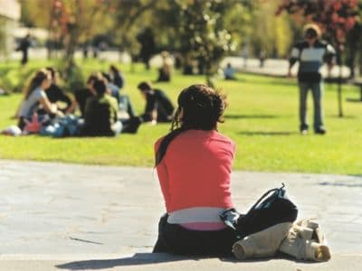 Bei einem Auslandsstudium triffst du immer viele neue Menschen und lernst neue Kulturen kennen. Frau mit Rücken zum Bild vor einer Grasfläche
