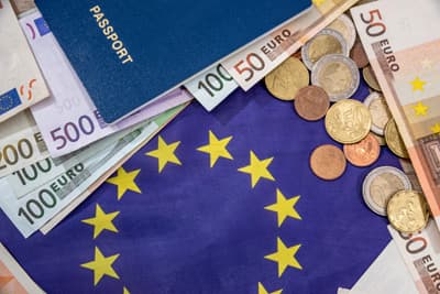 Geringere Studiengebühren für EU-Bürger in den Niederlanden Euroscheine und Reisepass auf einer Europa-Flagge