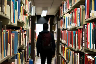 Mit einer guten Vorbereitung schafft ihr es durch die Aufnahmeprüfung! Student in einer Bibliothek